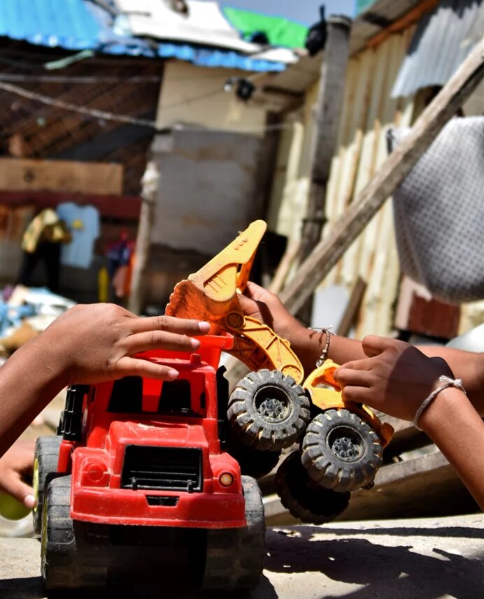 Children in the community play with a toy excavator 
