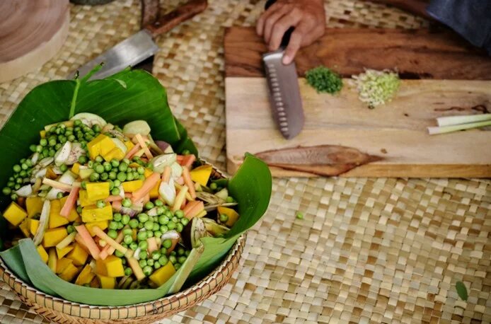 cuts fresh vegetables and other ingredients to make delicious samlor korko soup.