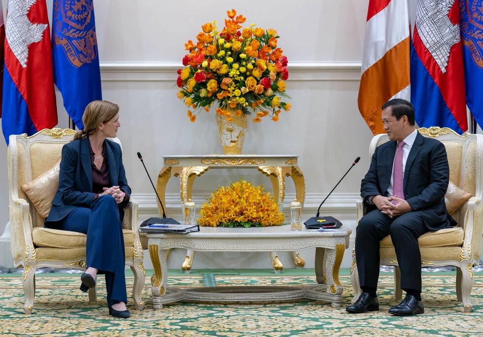 USAID-Administratorin Samantha Power und der kambodschanische Premierminister Hun Manet sitzen auf goldenen Sesseln. Im Hintergrund sind vielen Flaggen.