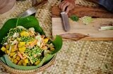 cuts fresh vegetables and other ingredients to make delicious samlor korko soup. 